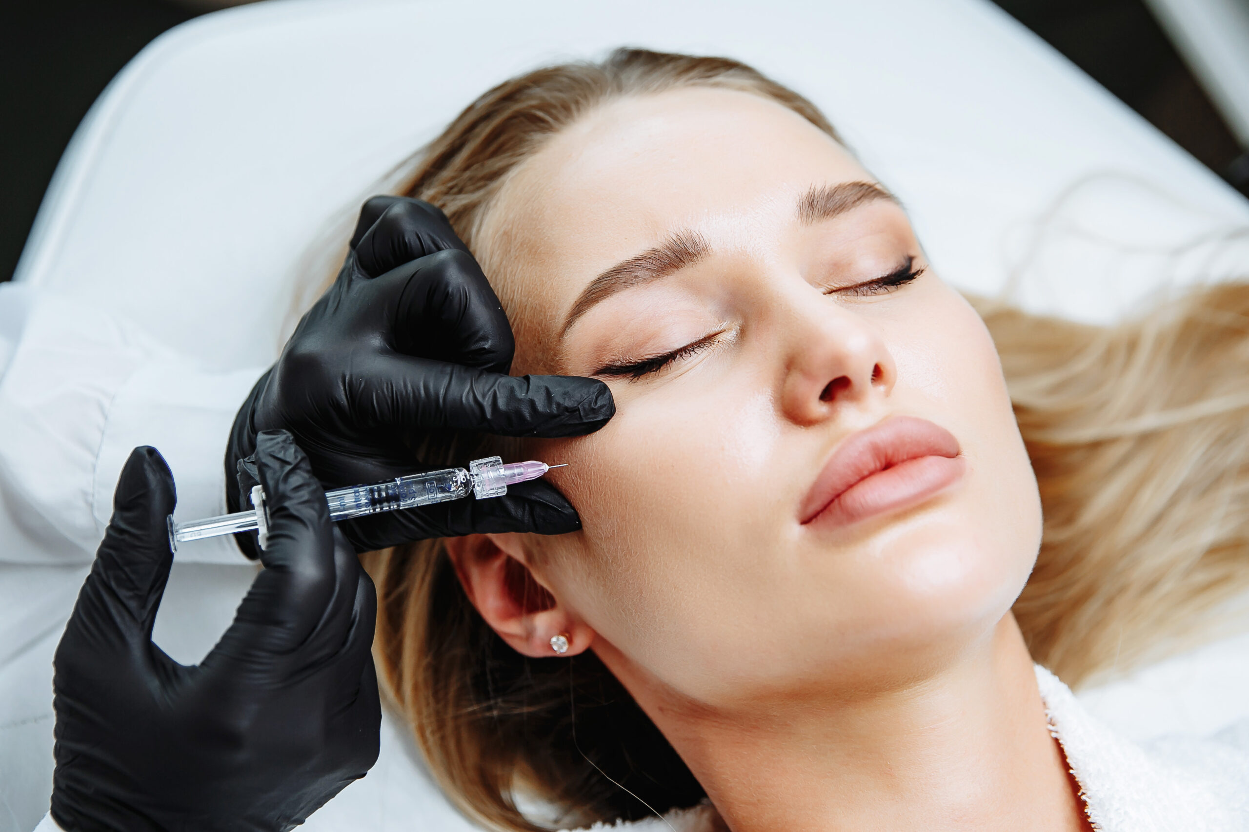 Young woman receiving plastic surgery injection on her face